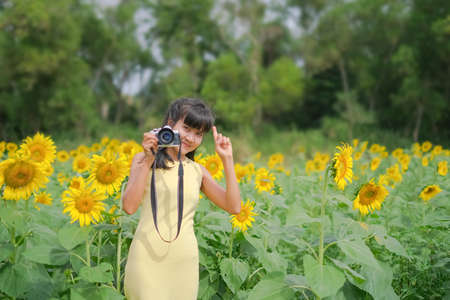 Woman holding camera for photographer on blur image of sunflower. she is rest day summer travel...