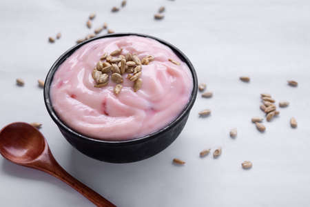 Strawberry yogurt with sunflower seeds in black cup. food for health concept.の写真素材