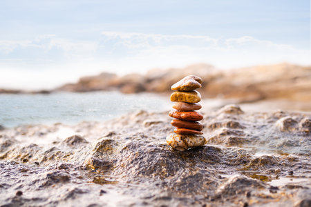 Stack of zen stone or pebble on rock with blue sea and blue sky blured. meditation , peace, harmony conceptual.の写真素材