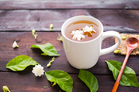Jasmine tea with flowers jasmine in white cup with wooden spoon on black wooden. hot tea from nature for health. drink of thailand and drink in morning. herbal drink concept.の写真素材