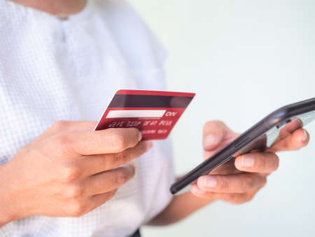 Close up woman holding credit card and mobile smartphone on white background.for shopping online buy...