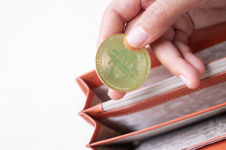 Finger holding Bitcoin crypto currency on wallet with white background. trade forex stock market...