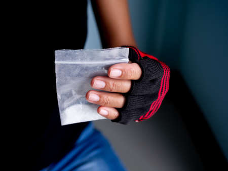 Hand holding amphetamine in plastic pack on black background. Dangerous drug. addictive substance. narcotic concept.の写真素材