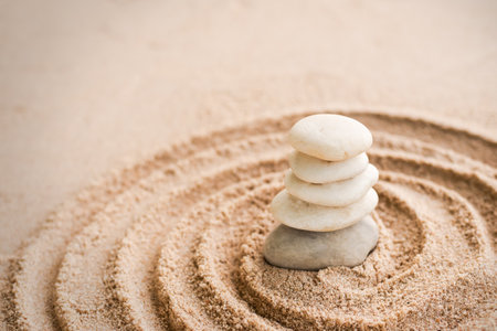 Japanese zen garden stone on sand beach. rock or pebbles with plumeria flowers with copy space. for aroma therapy spa on summer holidays. meditation wellness and tranquility Japanese concept.の写真素材