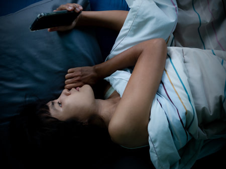 Woman sleep and holding mobile on the bed in night at room.couple married wait husband call back.she face sad and lonely. card poster for broken heart, love valentine day, break my heart,pain concept.の写真素材