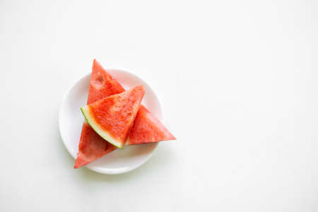 Watermelon in white plate on white background. flat lay with free space. tropical fresh organic fruits.sweet and red food in summer season. nature snack food for diet and healthy concept.の写真素材