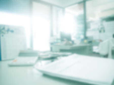 Blur in office inside background.over light on defocus  interior room workplace with calculator and document on table work space. business and finance backdrop concept.の写真素材