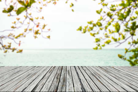 Leaves with wooden on sea. blank table on blue water shore and blue sky at coast. sunlight blur bokeh on ocean. mockup tropical seaside. Tourism relax vacation travel summer holidays.の写真素材