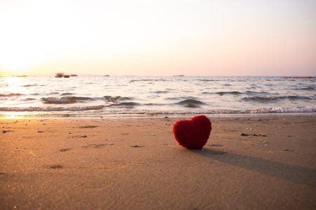 Heart shape on sand beach at coast with blur ocean and sunset background. card or poster for broken heart or love valentine romantic concept.の写真素材