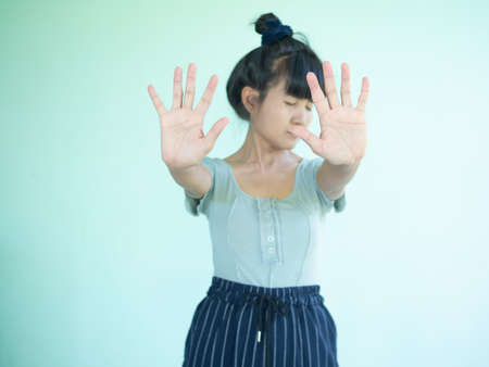 Portrait alone woman showing finger no symbols on wall green cement background. authentic skin tan and black hair asian woman and slim fit. she show hand stop and sad stress face.do not need concept.の写真素材