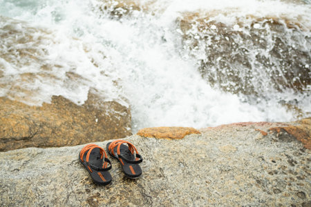 Flip flop on stone with splash wave white water at coast of sea ocean.tourist tropical vacation travel summer holidays nature seaside concept. woman sandals on rock.の写真素材