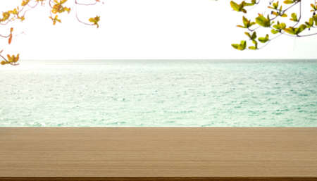 Wood table on blue sea and green  leave with bue sky background.montage mockup tabletop on water ocean backdrop.empty counter board display free space for presentaion product.tropical summer nature.の写真素材