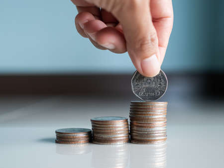 Stack coin.closeup finger woman holding money with blur pile cash on blue background.bank currency...
