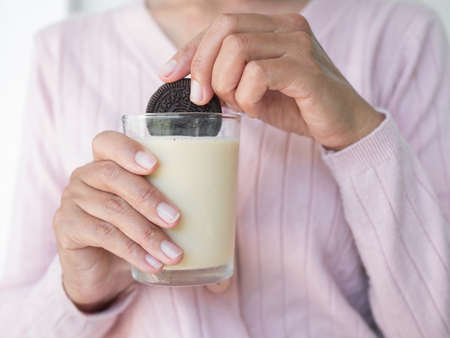 Woman holding Chocolate Cookies Dip Milk in glass close up.Breakfast for diet in morning.Food have hight protein and calcium. snack for break. cow milk for drink.の写真素材