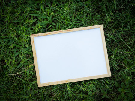 Blank white board on Green Grass background.Tropical mockup signboard on plant garden nature. empty template board spring or summer.showing card poster free space for business environmental.の写真素材