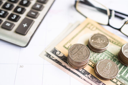 Stack Coin on Bank Note with Blur Calculator and glasses on white Table Background,Investment  Income and Saving for 2023 New Year,Business or Finance concept.の写真素材