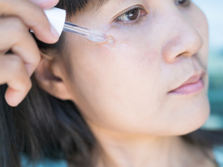 Woman Apply Serum Vitamin c Moisturizer on Face Close up,Authentic Black Eyes and Black Hair Asian Thailand,Makeup Cream for Protection Sunscreen,Cosmetic for Beauty and Younger Face concept.の写真素材