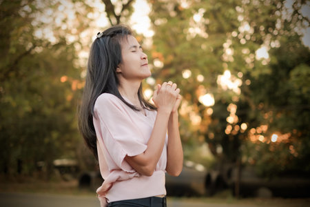Woman standing with eyes closed on blur bokeh and tree on sun set. tourist travel autumn in holidays.authentic skin tan and black hair female asian thailand.pray calm vacation relax lifestyle concep.の写真素材