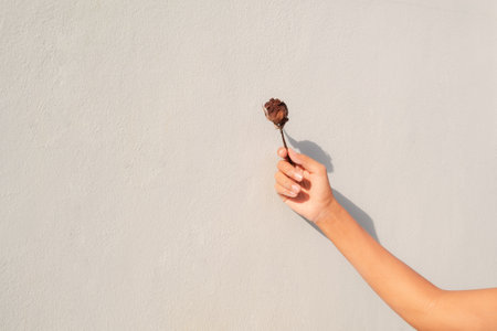 Hand woman holding dry red rose with dark shadow on old and dirty cement wall background. broken heart symbols. hopeless in love, problem, sad, lonely concept.の写真素材