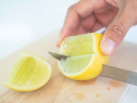 Knife Cutting Lemon Slice on wooden cutting board with white background,Yellow Lime Citron Raw Food Orgarnic Nature Tropical Fruits,Cooking Juice Drink in Kitchen,Hight Vitamin C for Diet Health.の写真素材