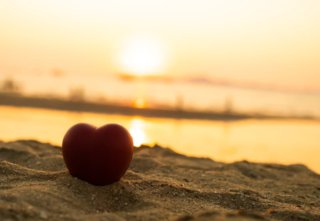 Red Heart Shape on Sand Beach at Coast in Sunset Gold Twilight Background,Card Poster for Sad,Couple Pain,Holiday Valentine Day,Marriagn Disappointed Concept,Design Vintage Romantic Sign,Broken Heart.の写真素材