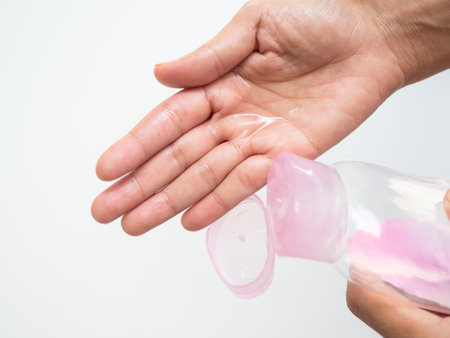 Baby Oil on Palm on White Background,Woman Pour Massage on Hand for Apply Body and Face after Shower in Bathroom at Home for Nourishes Skin to be Soft and Moisturized,Cosmetic for Beauty and Health.の写真素材