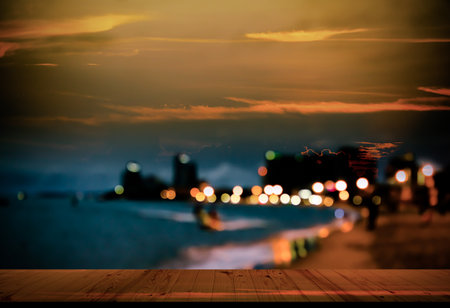 Table on Blur Light Bokeh and Sea Beach Sand Summer Party Night Bar Background,Desk Counter with View Sunset Outdoor Dinner at Restaurant,Sunrise City Building,Touris Travel Tropical Ocean Holidays.の写真素材