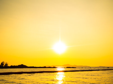 Sunset Sky with Sea Ocean Background,Golden Cloud Horizon Sunrise on Sand Beach and Calm Water Nature,Yellow Sunlight Down Tropical Summer Beautiful Landscape,Wave Shore Island at Coast,View Seascape.の写真素材