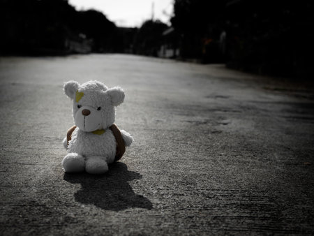 Alone Teddy Bear sitting with Dark Black on Street, Abandoned Doll, Concept for Broken Heart Couple, Sad, Lonely, International Missing Children, Strong, Gloomy Day, Alone Unwanted Cute Doll lots.の写真素材