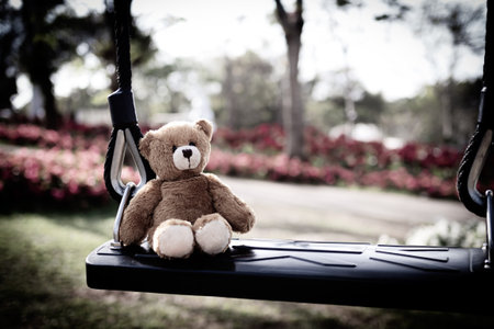 Teddy Bear sitting on Swing, Symbols Violence Domestic Abuse Sad grief Lonely Depressed Emotion Sorrow, Child Kid Fear Scared, Toy Card for Worried and Broken Heart, International Children is day.の写真素材