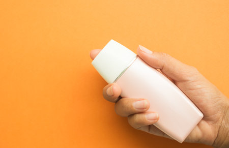 Bottle Cosmetic mockup Package Plastic Product Cream Tube Lotion Container Beauty Summer, hand woman holding Sunscreen Blank on Orange Backgroundの写真素材