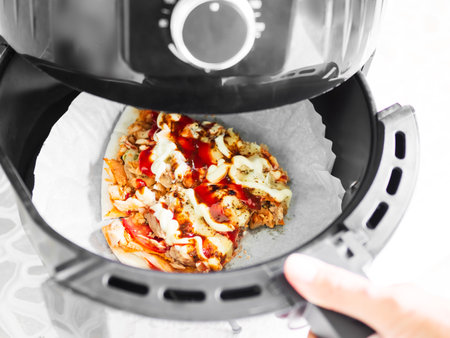 Pizza in Fryer Air Basket New Cooker Hot Warm Food in Oven at Kitchen Italian Fastfood Piece in Utensilの写真素材