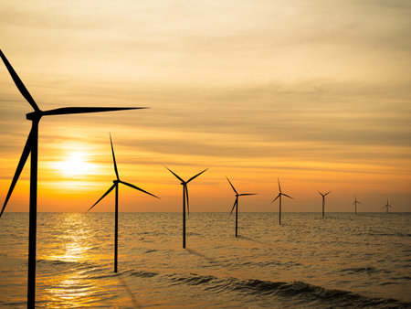Wind Mill Turbine on Sea Offshore Farm, Energy Windmill Sustainable with Red Sunset Ocean Industry on Water, Power Electric Plant view Landscape, Powerplant Windfarm Change for Co2 Environment.の写真素材