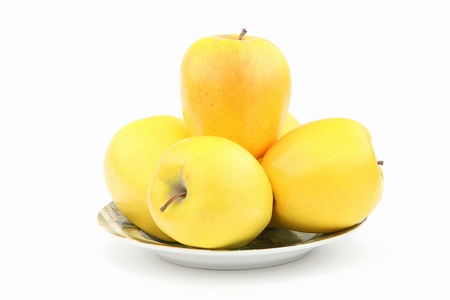 Yellow apples in a plate over white の写真素材