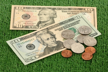 Dollars and coins on a green background of artificial grass の写真素材