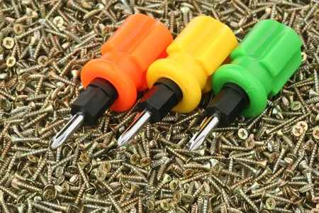 Three multi-coloured screw-drivers against small yellow screws 
