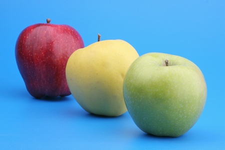 Three multi-coloured apples on a blue background の写真素材