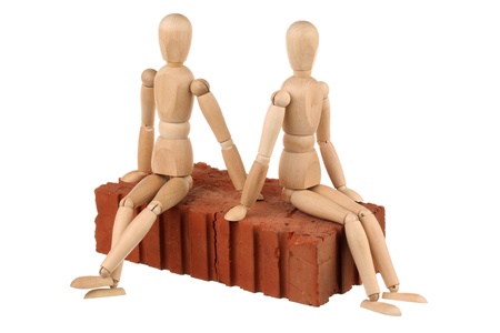 Two dummy sitting on a red brick isolated on white backgroundの写真素材