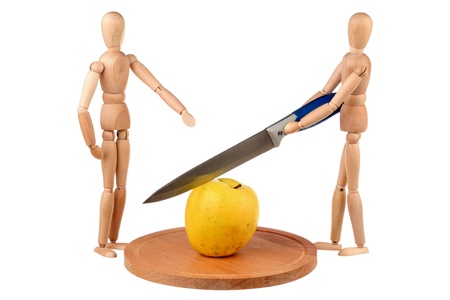 Two wooden dummy divide one yellow apple isolated on white background