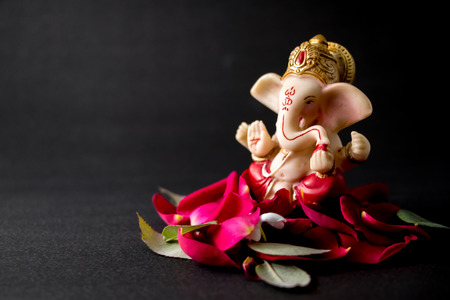 Lord Ganesha Idol with rose petals, white flowers and leaves on Black background, Ganesh poojaの写真素材
