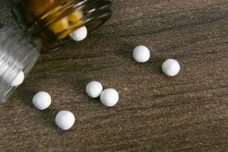 Close image of Scattered globules and homeopathic medicine bottles on wood backgroundの写真素材