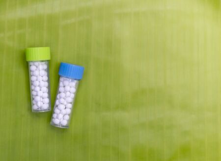 Natural Homeopathy Concept - A homeopathy concept with homeopathic pills bottles on banana leaf...