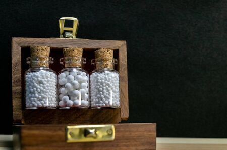 Close view of homeopathy medicine bottles in wooden old box on wood and dark backgroundの写真素材