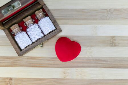 Wooden old medicine box with homeopathic pills glass bottles on wood background and red heart. medicine conceptの写真素材