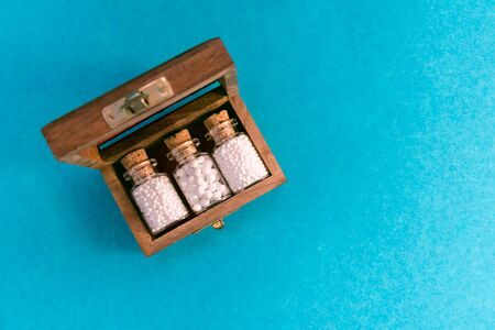 Homeopathic medicine glass bottles with cork in wooden old box on blue backgroundの写真素材