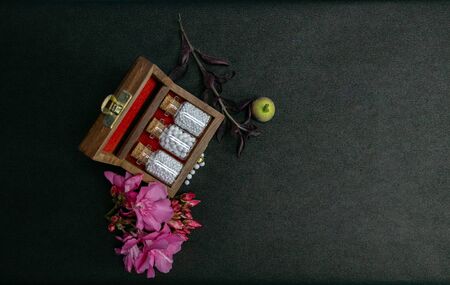 Top view of homeopathy pill bottles with cork in wooden classic box and fresh wild pink flowers with scattered globules on dark surface. Homeopathic medicine conceptの写真素材