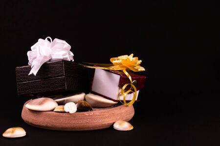 Decorated gift boxes and spreaded seashells on black backgroundの写真素材