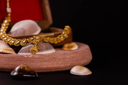 Golden necklace around wooden box and seashells on dark backgroundの写真素材