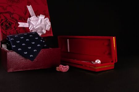Anniversary gift concept. Beautiful silver pearl necklace in red box, candy wih blue tie and...