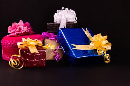 Decorated gift boxes with colorful ribbons and bows on dark surface. Gifts concept
